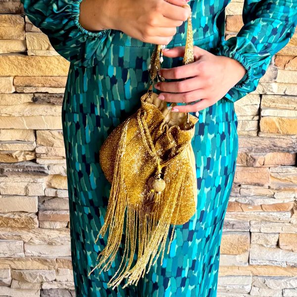 Descubre el Bolso Bombonera Raipur Dorado, elaborado artesanalmente en India. Un bolso de fiesta con pedrería, flecos y cadena, perfecto para bodas, eventos e invitadas.